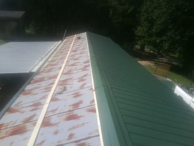 Old rusted panels beside newly installed green metal roofing — Wind Damage Roof Repair by Roofing Brothers in North Judson
