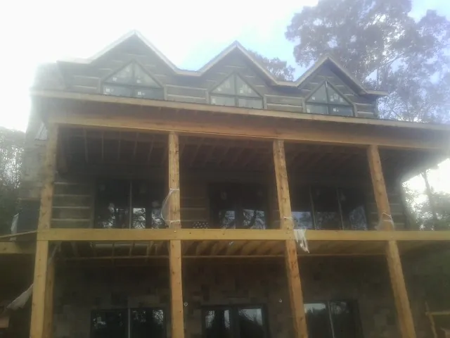 Dormers and porch framing on a large log home under construction — Roof Coating work by our crew in North Judson