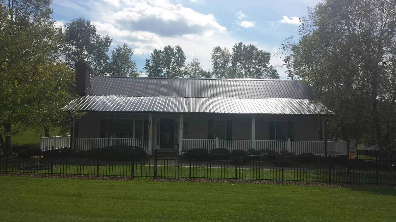 Gray metal roof on a brick ranch with a full width front porch — Gutter Guard Installation work by our crew in North Judson