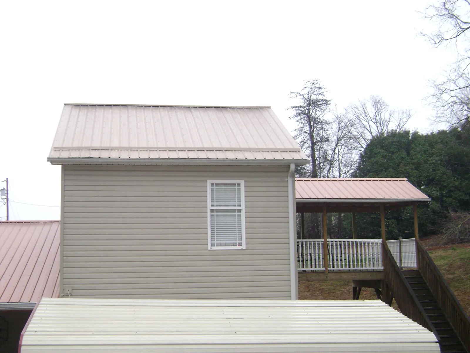 Tan metal roofs on a two story addition and attached porch, from a Roof Replacement job in North Judson