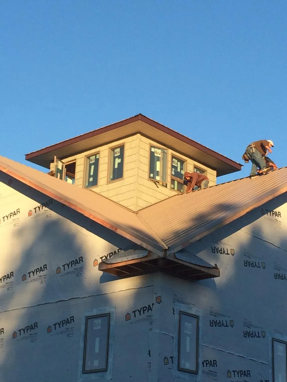 Roofers working around a rooftop cupola on a new metal roof at sunset — Roof Waterproofing in North Judson by Roofing Brothers